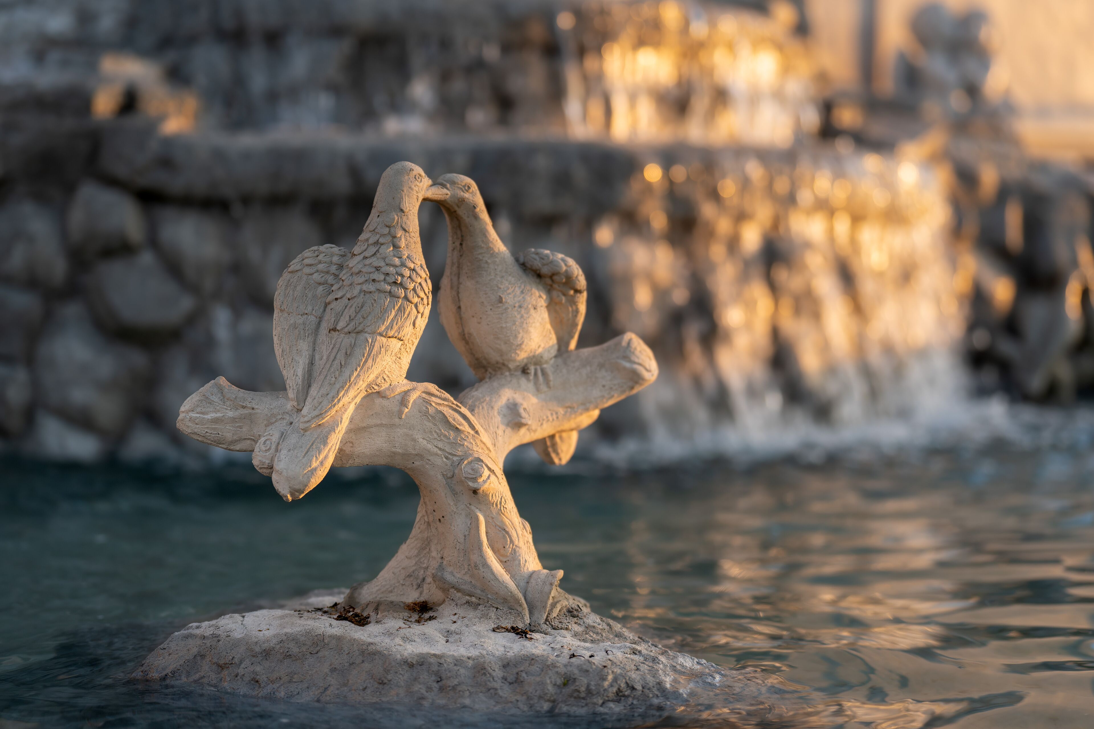 A sculpture of two birds on a rock by a body of water.