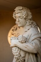 Primer plano de una estatua de mármol con detalles intrincados y un fondo circular.