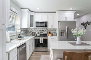 A modern kitchen with white cabinetry, stainless steel appliances, and a central island.