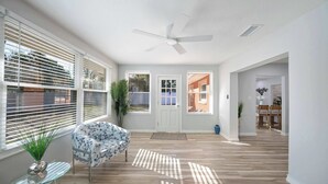 A spacious room with a ceiling fan, large windows with blinds, a door, and a dining area in the background. - Spacious House w/ Patio & Fenced Yard (Lakeland)
