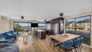 A modern kitchen with a large island, bar stools, and a dining table with chairs.