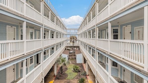 A corridor with multiple balconies and a central courtyard with plants. - Condo w/Beach/Pool Views Over-sized Balcony - w/d in unit & bidet (Galveston)
