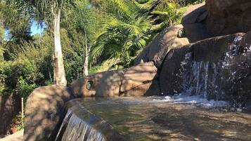 A waterfall cascading over a rock formation surrounded by lush greenery.