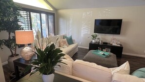 Ein Wohnzimmer mit Sofa, Couchtisch, Fernseher und Lampe.