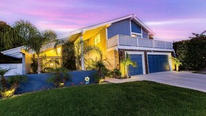 Ein modernes, zweistöckiges Haus mit Balkon, Garage und gepflegtem Rasen.