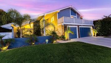 A modern two-story house with a balcony, a garage, and a well-maintained lawn.