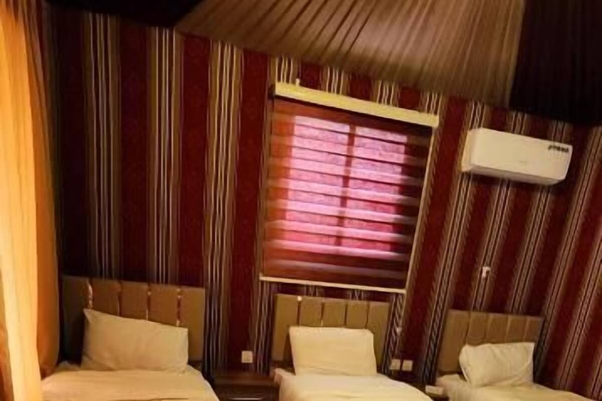 Habitación de hotel con dos camas, cortinas a rayas y suelo de baldosas.