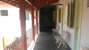 A covered corridor with benches, a railing, and a staircase leading to an upper level. - Pousada Samambaia  (Sao Lourenco)