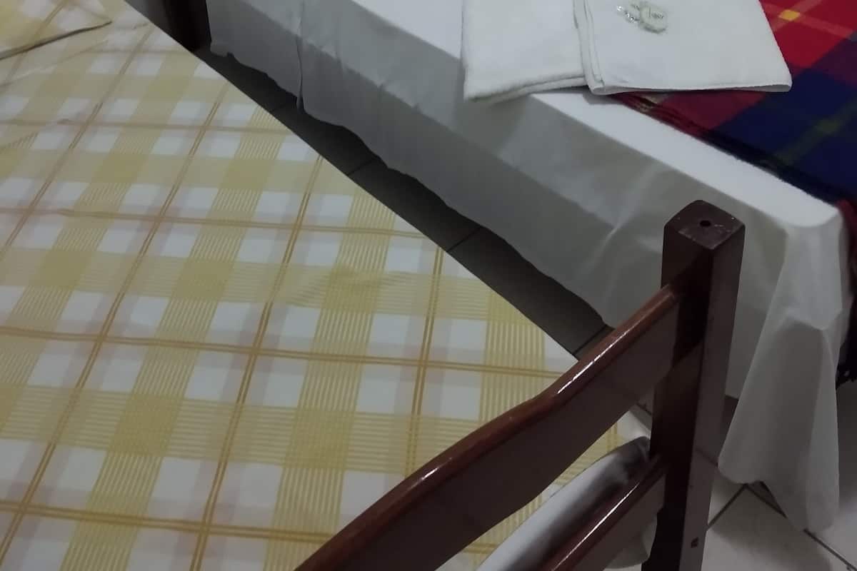 Una habitación con dos camas, una con colcha a cuadros amarillos y la otra con colcha blanca.