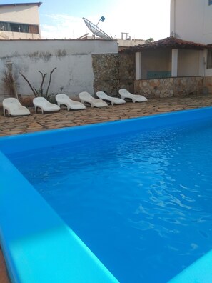 Ein Swimmingpool mit weißen Liegestühlen und einer Steinmauer.
