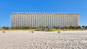 A large hotel with a long facade, multiple floors, and a flat roof. - Steps to Shore: PCB Condo w/ Pool Access + Views! (Panama City Beach)