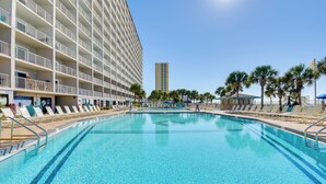 A hotel pool area with sun loungers and a large building with balconies. - Steps to Shore: PCB Condo w/ Pool Access + Views! (Panama City Beach)