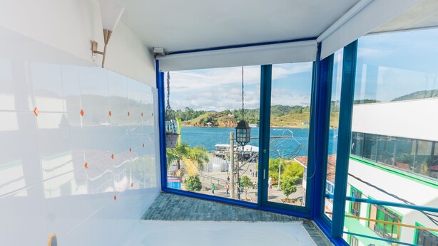 A bathroom with a large bathtub, a view of the sea, and a tiled floor. - Hotel Guatatur (Guatapé)