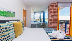 A hotel room with a bed, a view of a bridge, and a balcony with a railing. - Hotel Guatatur (Guatapé)