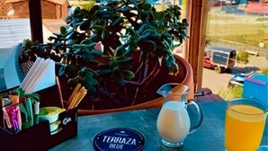 A table with breakfast items, a view of the sea, and a sign reading "Terrazza Blue". - Hotel Guatatur (Guatapé)