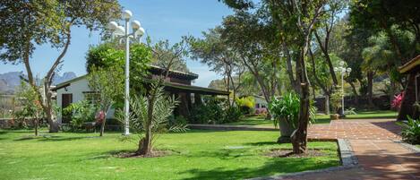 A well-maintained garden with a paved walkway, a gazebo, and a building with a tiled roof.
