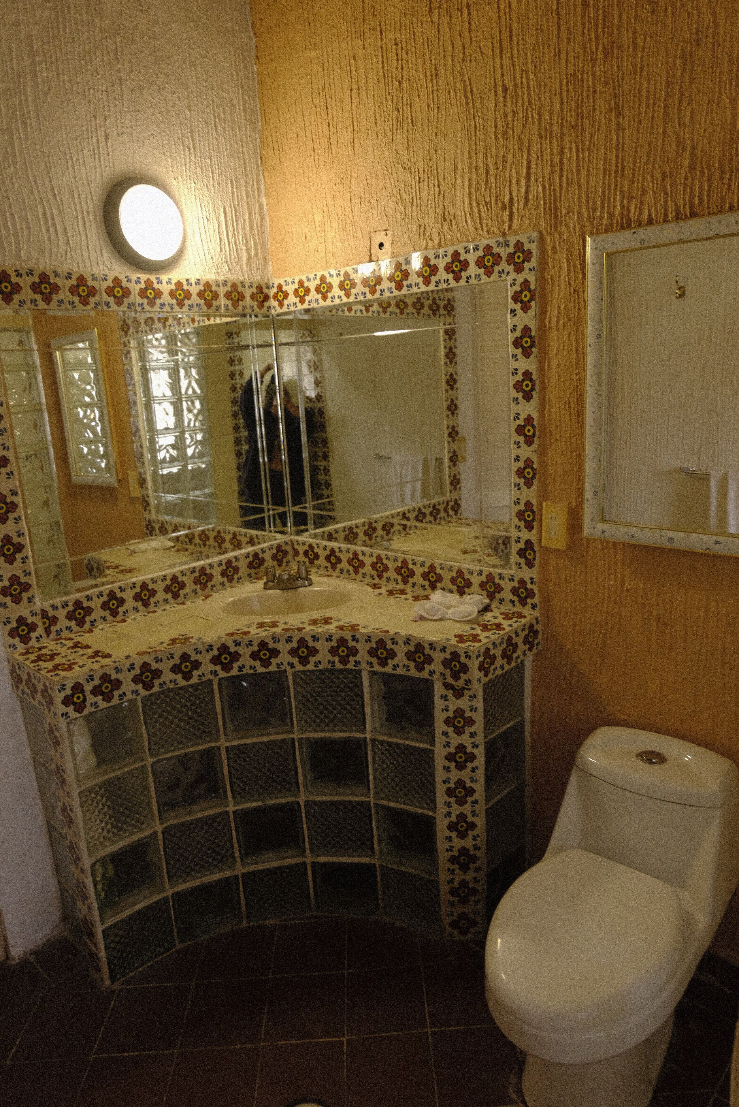 A bathroom with a floral-patterned sink, a mirror, and a toilet.