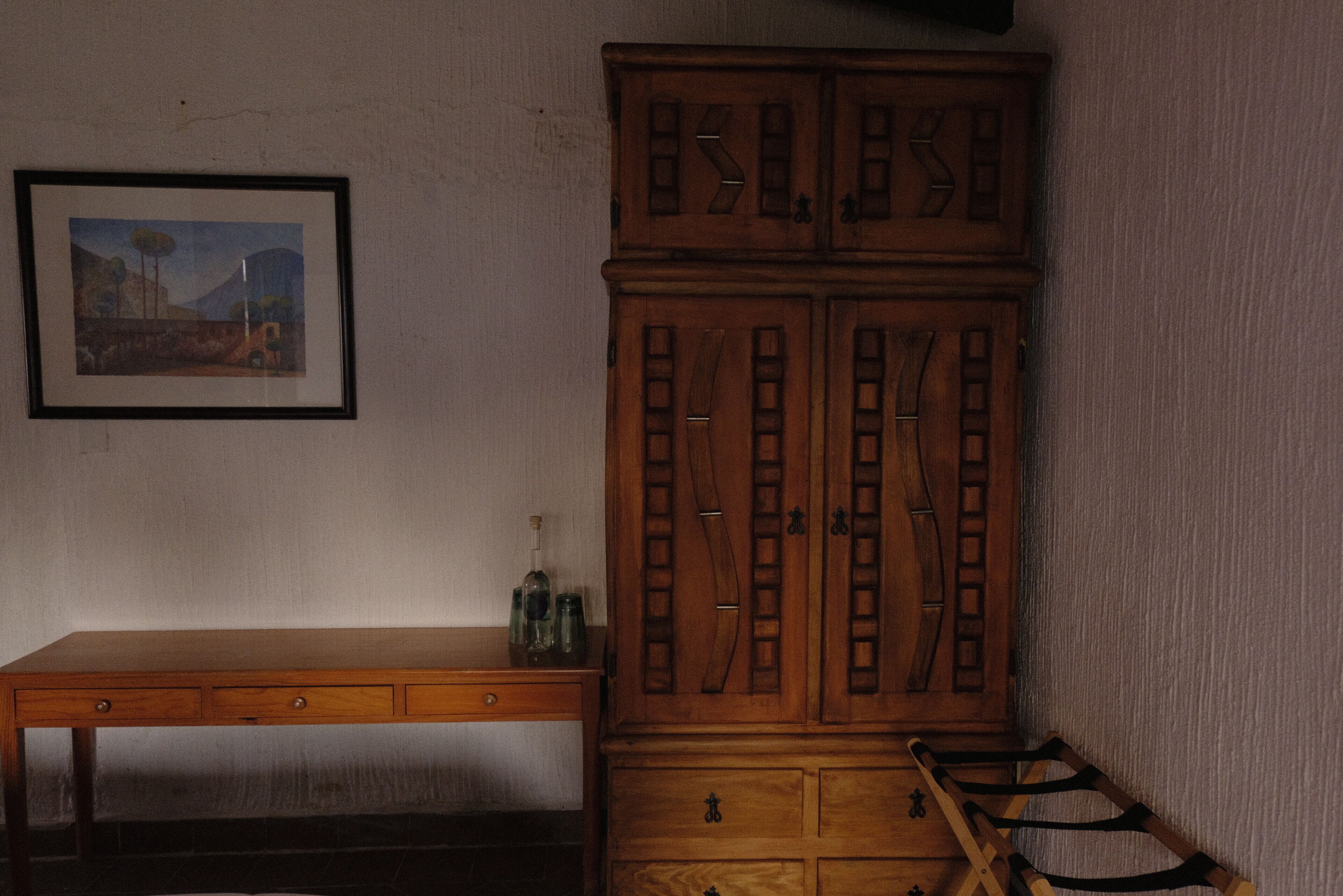 Un mueble de madera con cajones y una mesita con botellas.