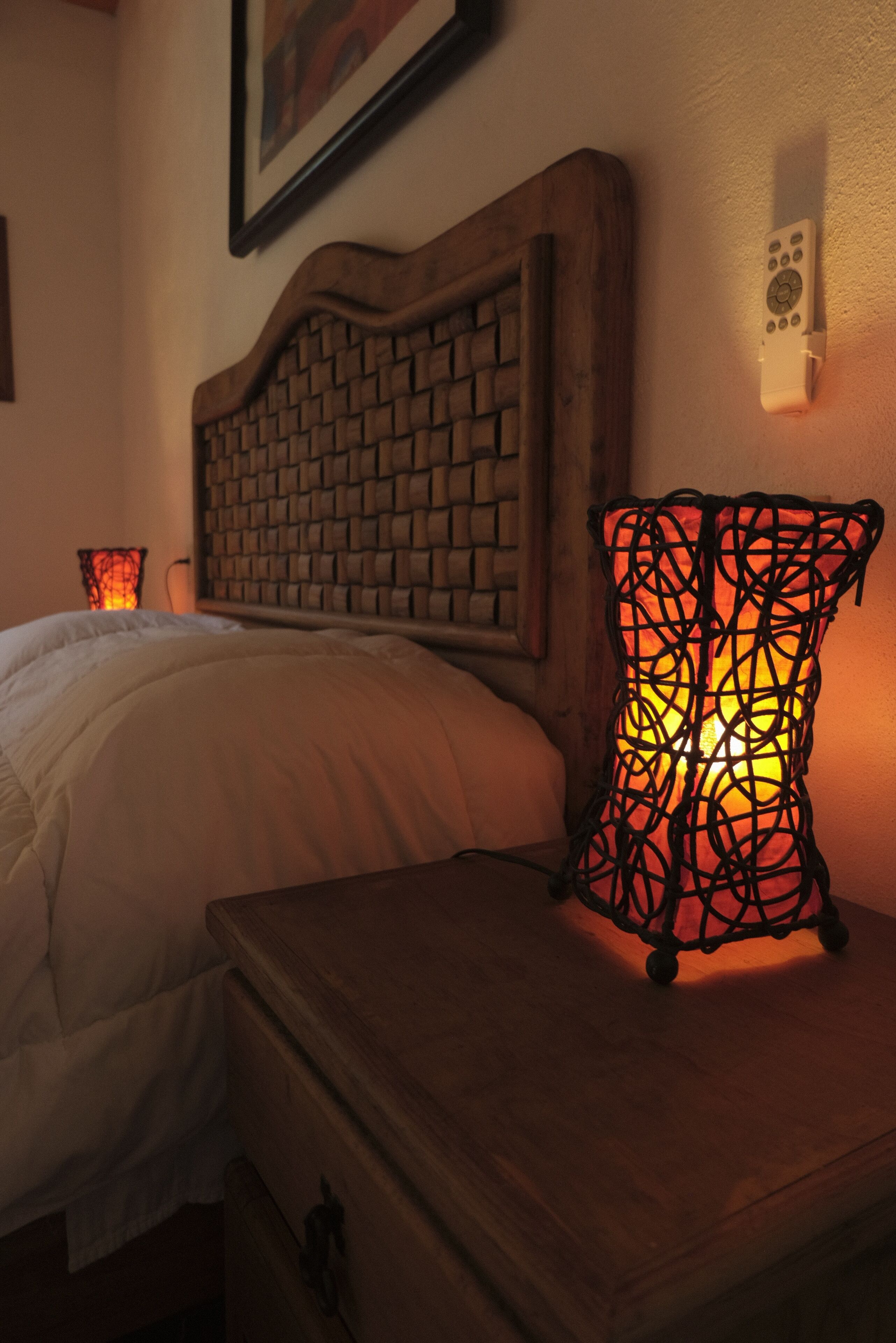 Un lit avec une tête de lit en bois, une table de chevet et un luminaire fixé au mur.