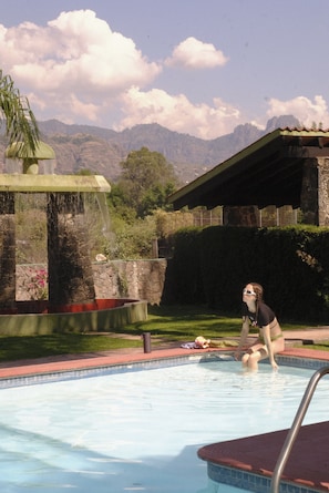 A person sitting by a pool with mountains in the background. - Villlas Mexiko (Tepoztlán)