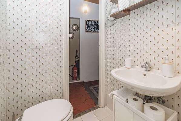 Un baño con baldosas estampadas con motivos florales, un lavamanos blanco y un inodoro.