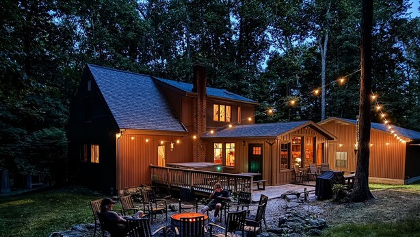 Een houten huis met twee verdiepingen, een terras en een buiten zitgedeelte.