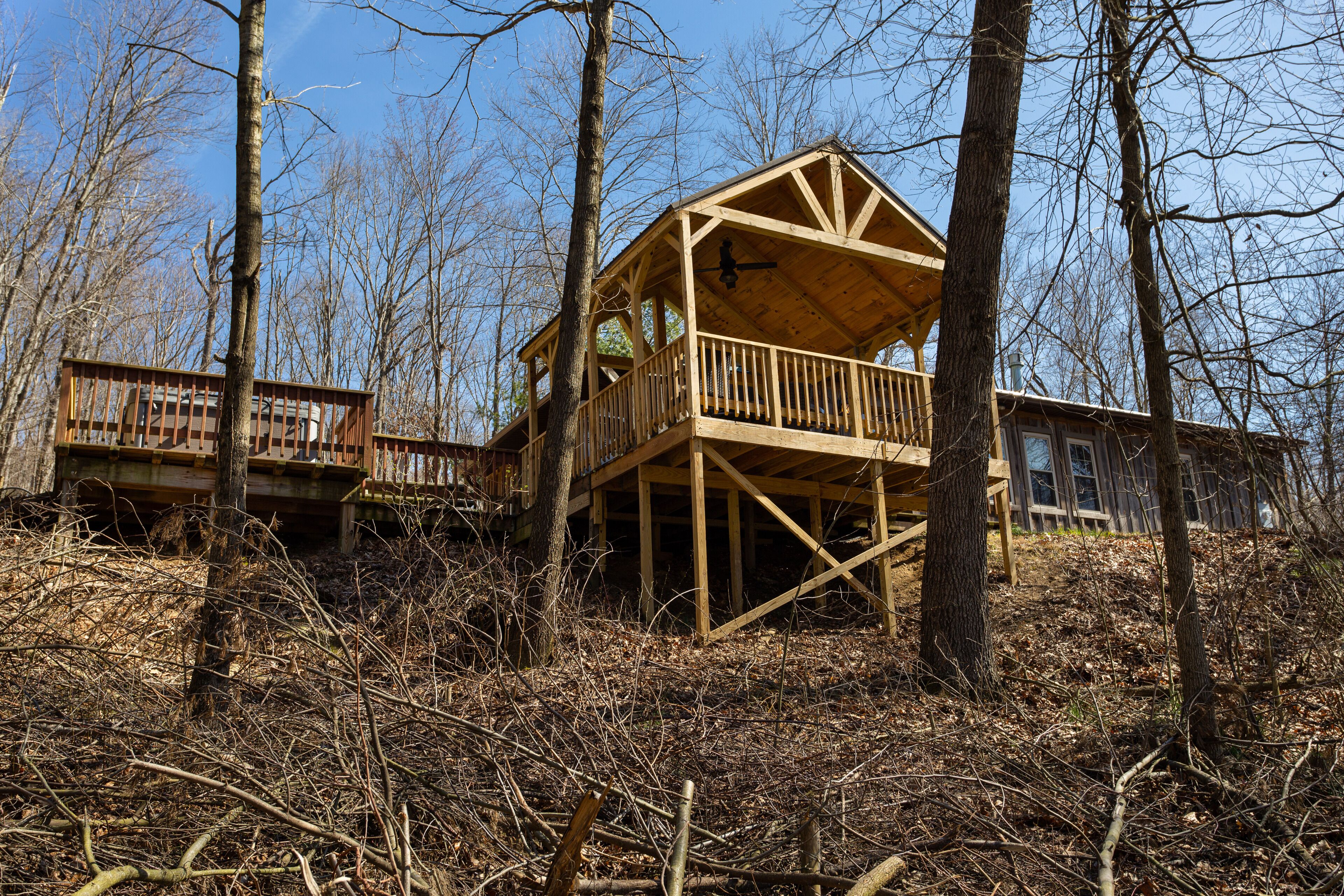 A wooden cabin with a balcony, surrounded by trees and a wooden deck.