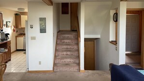 A staircase leading to a second floor, a kitchen area with a refrigerator, and a dining area with a table and chairs. - Peaceful, Sunlit Condo on Haystack Golf Course (Wilmington)