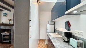 Moderni keittiö, jossa on ruutukuviollinen lattia, kahvinkeitin, leivänpaahdin ja pesuallas.