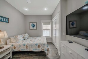 A bedroom with a bed, a TV, a desk, and a window.