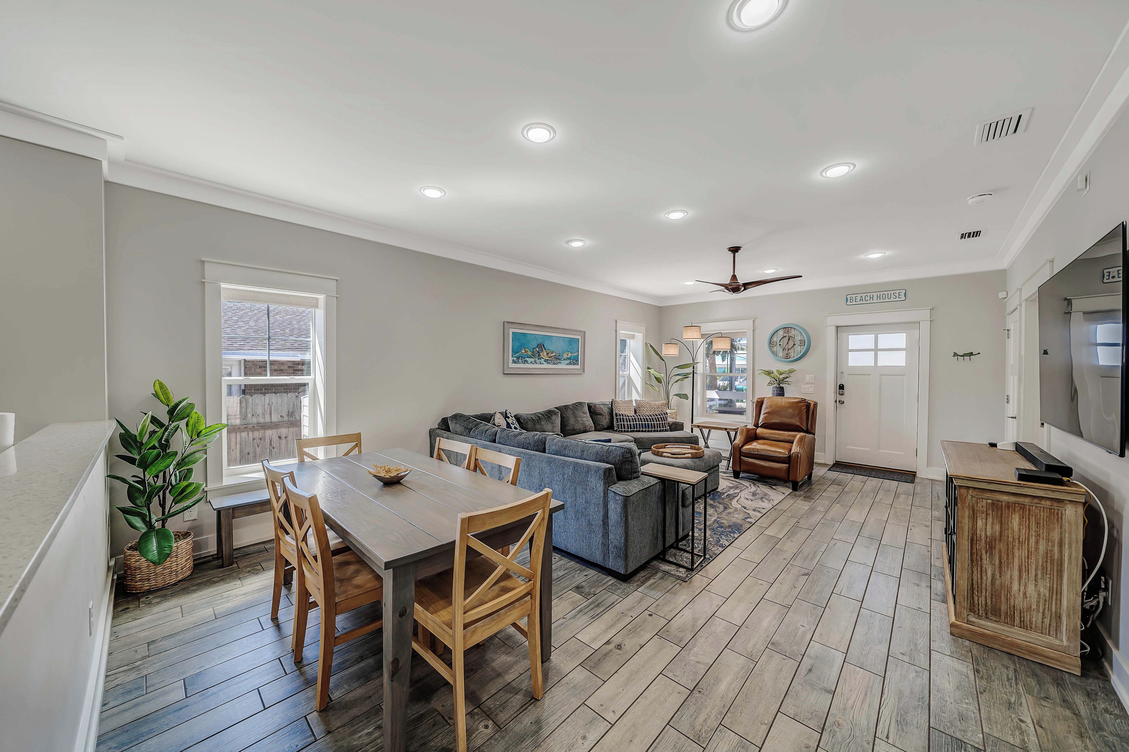 A spacious living area with a dining table, sofa, and a ceiling fan.