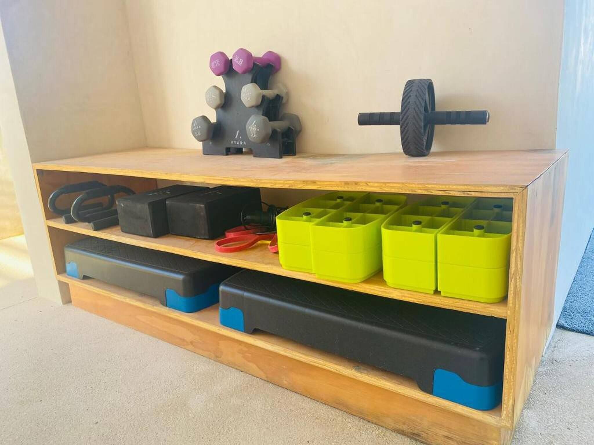 A wooden shelf with various storage bins and exercise equipment.