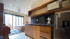 A modern kitchen with wooden cabinets, a black refrigerator, and a coffee maker. - Studio By The Pool, Jacuzzi (Tulum)