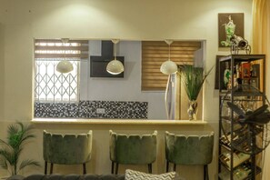 A modern kitchen with a large window, two pendant lights, and a bar area with a mirror. - 3D's Luxury Properties: Gated Estate
 (Accra)