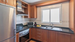 Une cuisine compacte équipée d’un réfrigérateur, d’un four à micro-ondes, d’une cuisinière et d’un évier.