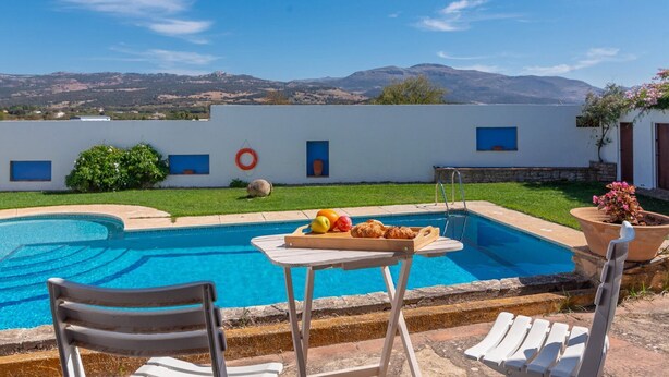 Un área de piscina con una mesa dispuesta para comer, una silla y una tumbona.