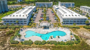 Um resort com vários edifícios, uma área de piscina central e vista para o oceano.