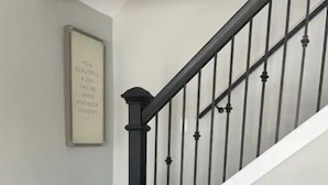A staircase with black railings and a dark wood floor. - Whispering Pines Lake House (Gladwin)