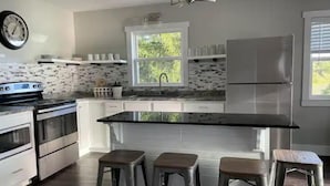 A modern kitchen with a central island, bar stools, a built-in oven, and a refrigerator. - Whispering Pines Lake House (Gladwin)