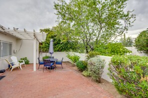 A patio with a brick floor, white pergola, and a table with chairs. - Tucson Townhome w/ Shared Pool in 55 + Community! (Tucson)