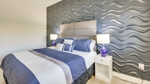 Une chambre à coucher avec un lit, deux tables de chevet et un mur orné d’un motif ondulé.