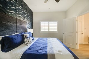Una camera da letto con un letto grande, una testiera dal design ondulato, una finestra con tende e una porta.