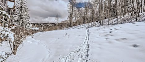 Une piste de ski enneigée, parsemée d’empreintes de pas, avec un bâtiment en bois sur la gauche et des arbres sans feuilles.