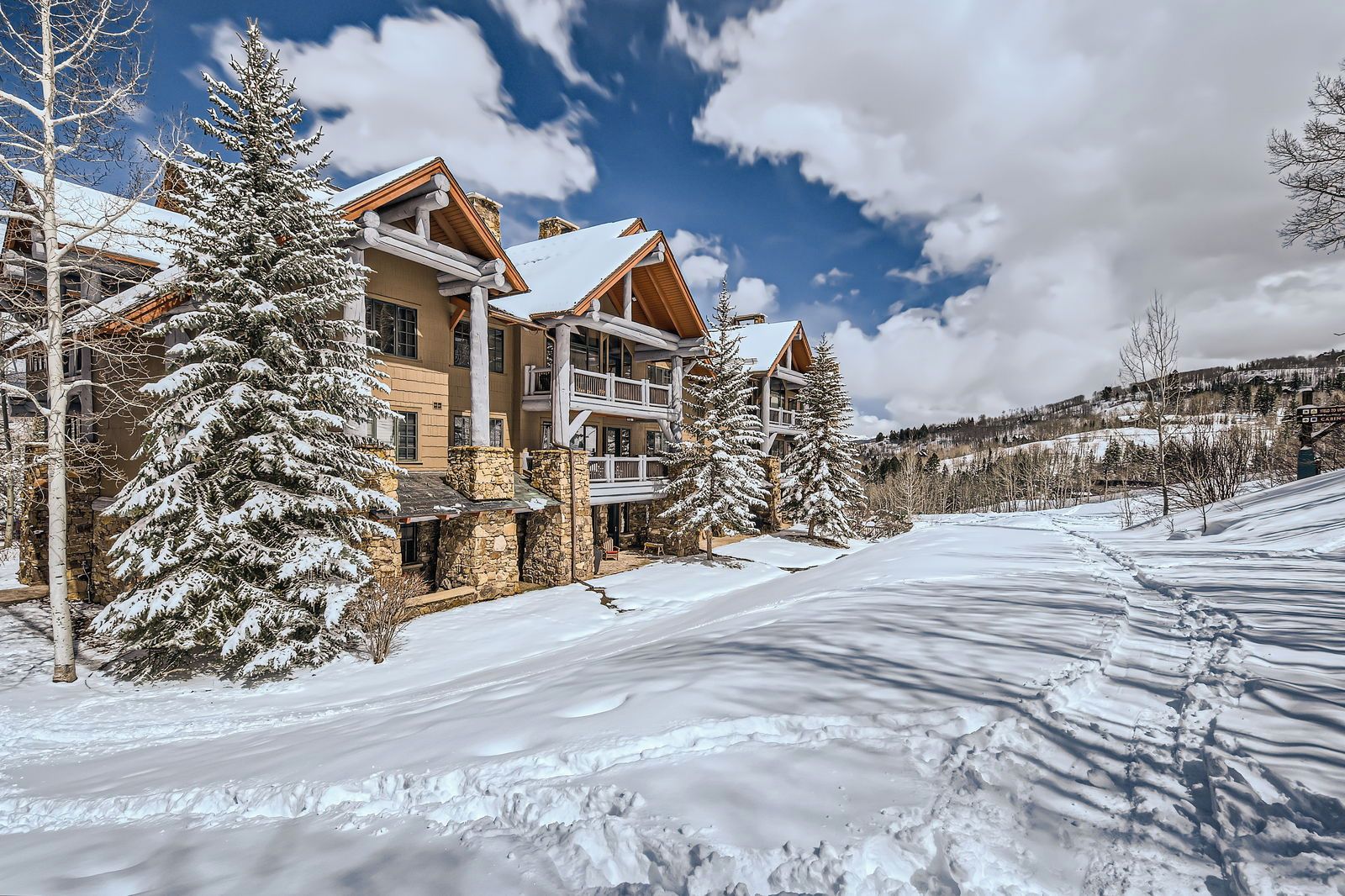 A multi-story lodge with a stone facade, wooden balconies, and snow-covered surroundings.