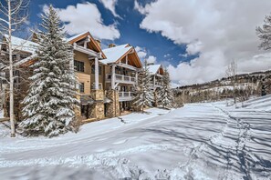 A multi-story lodge with a stone facade, wooden balconies, and snow-covered surroundings. - Charlie's Slopeside: Bear Paw, Ski-In/Out, Sleeps 8, Bachelor Gulch + Ritz Pool & Hot Tub Access (Beaver Creek)