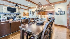 A spacious living room with a large wooden dining table, a fireplace, and a stone accent wall. - Spacious 3BR ski-in/out Beaver Creek condo with valley views. (Beaver Creek)