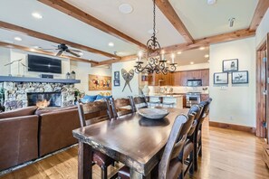 Un salon spacieux avec une grande table à manger en bois, une cheminée et un mur décoratif en pierre.