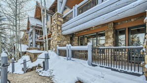 A snow-covered stone building with a wooden deck and a metal railing. - Spacious 3BR ski-in/out Beaver Creek condo with valley views. (Beaver Creek)