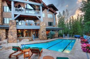 A two-story lodge with a stone facade, a pool, and outdoor seating. - Charlie's Slopeside: Bear Paw, Ski-In/Out, Sleeps 8, Bachelor Gulch + Ritz Pool & Hot Tub Access (Beaver Creek)