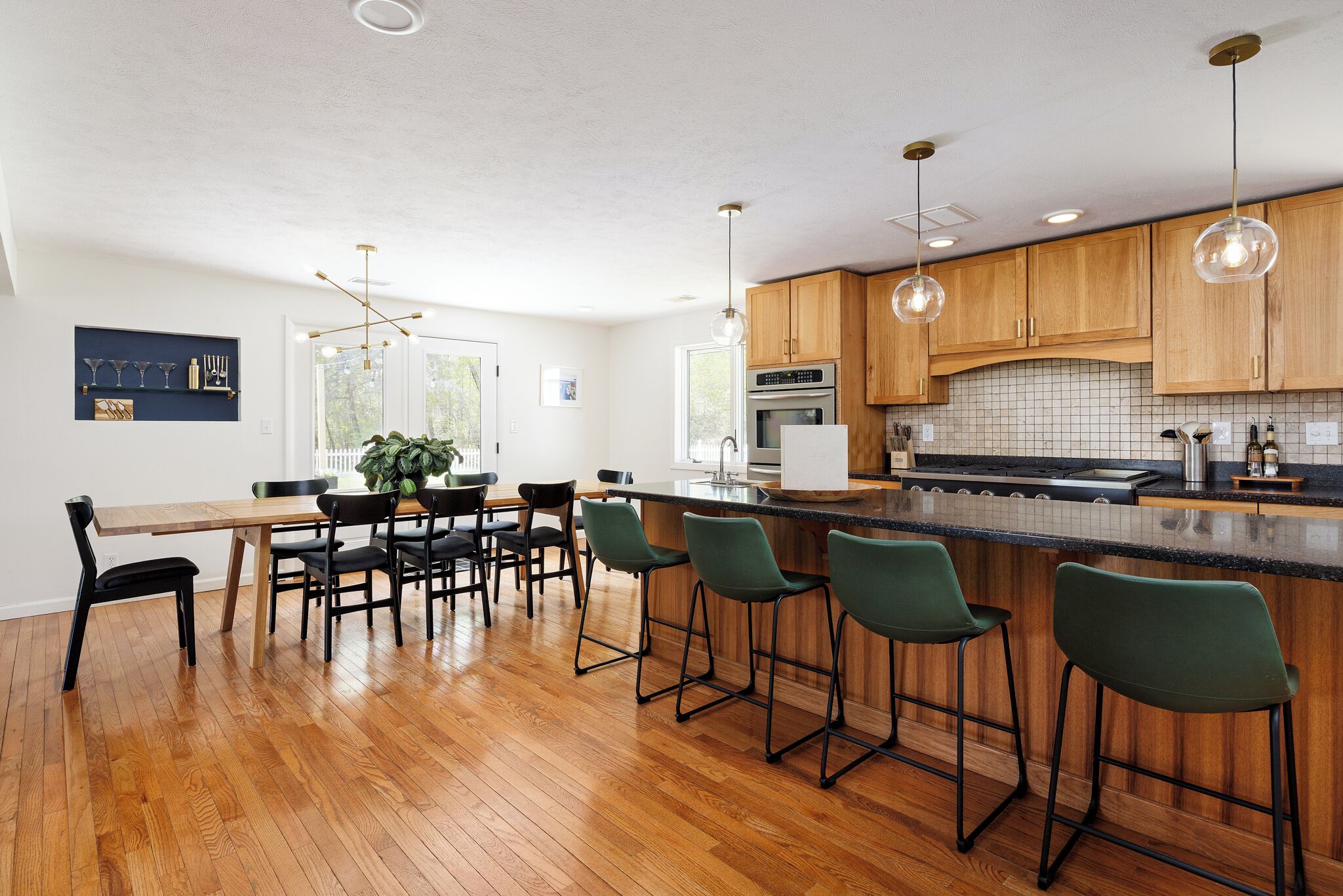 A modern kitchen with wooden cabinets, a central island with bar stools, and pendant lighting.